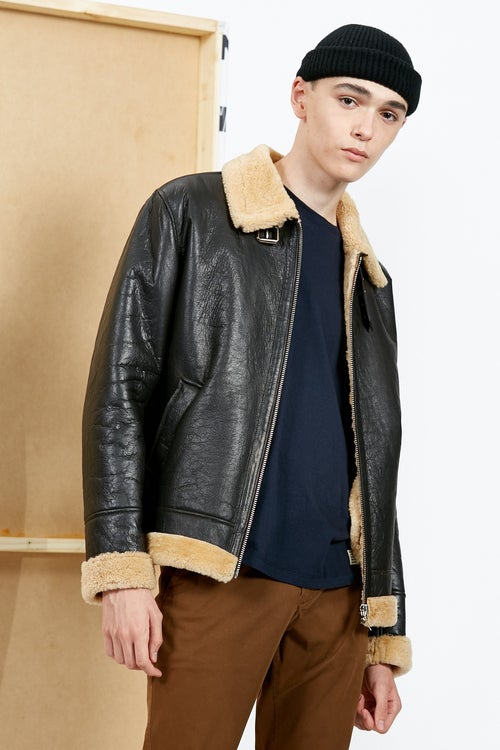 Bowen Belfort posing in a black cap, leather jacket and a brown pant.